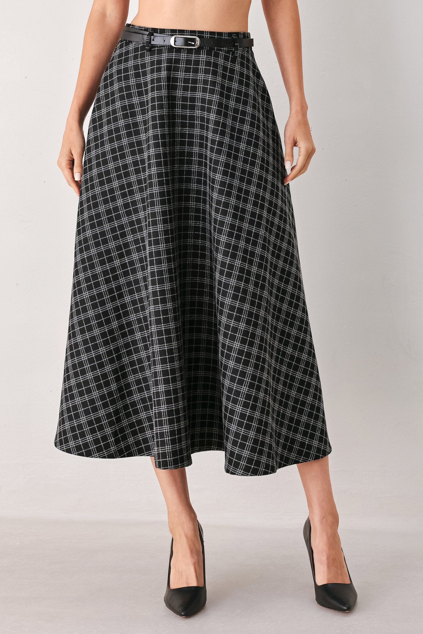 A woman wearing a black and gray plaid midi skirt with a black belt | FREEMARKET