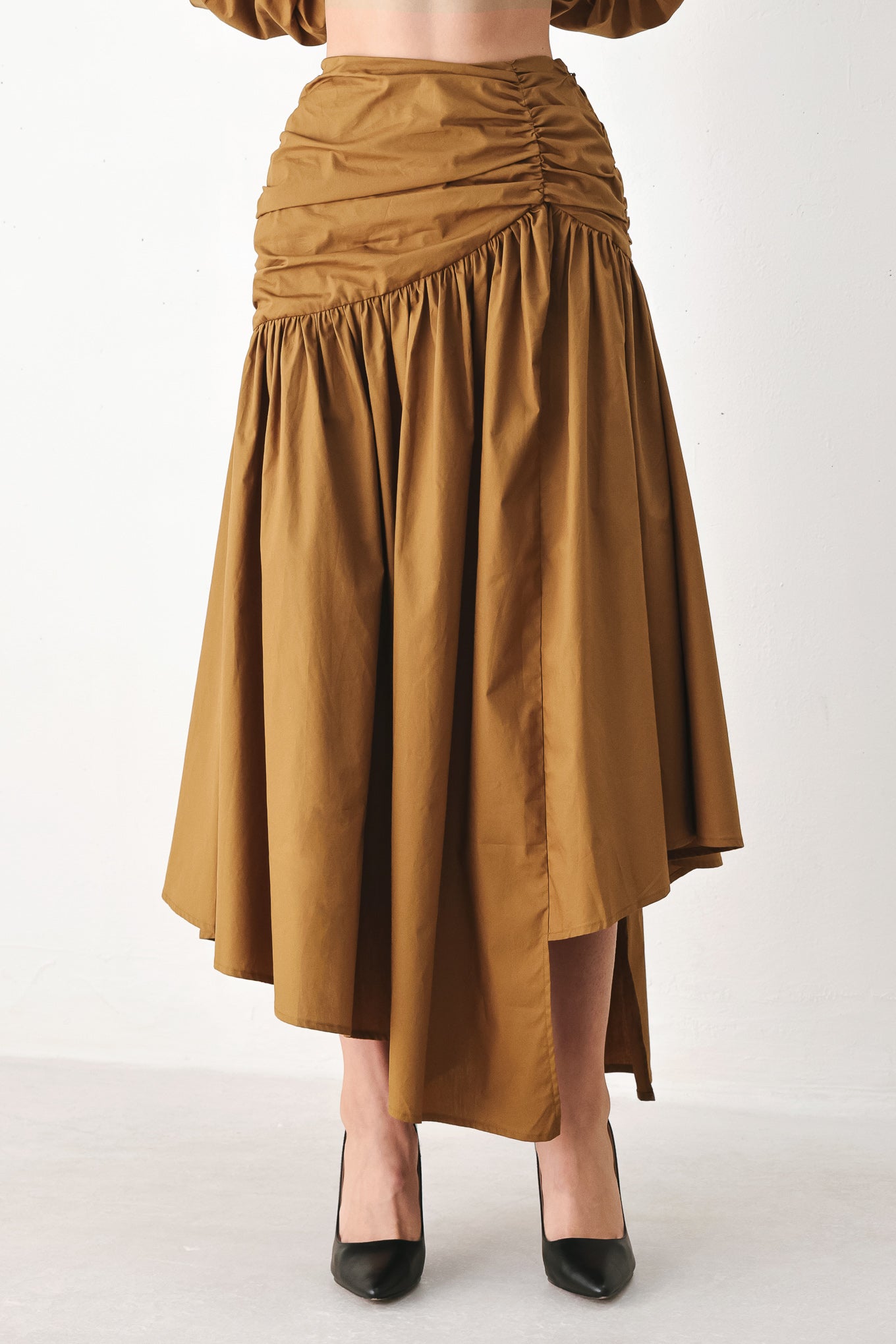 A model wearing a high-waisted, ruched A-line midi skirt in a warm caramel brown color | FREEMARKET