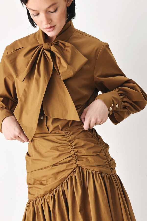 A model wearing a high-waisted, ruched A-line midi skirt in a warm caramel brown color | FREEMARKET