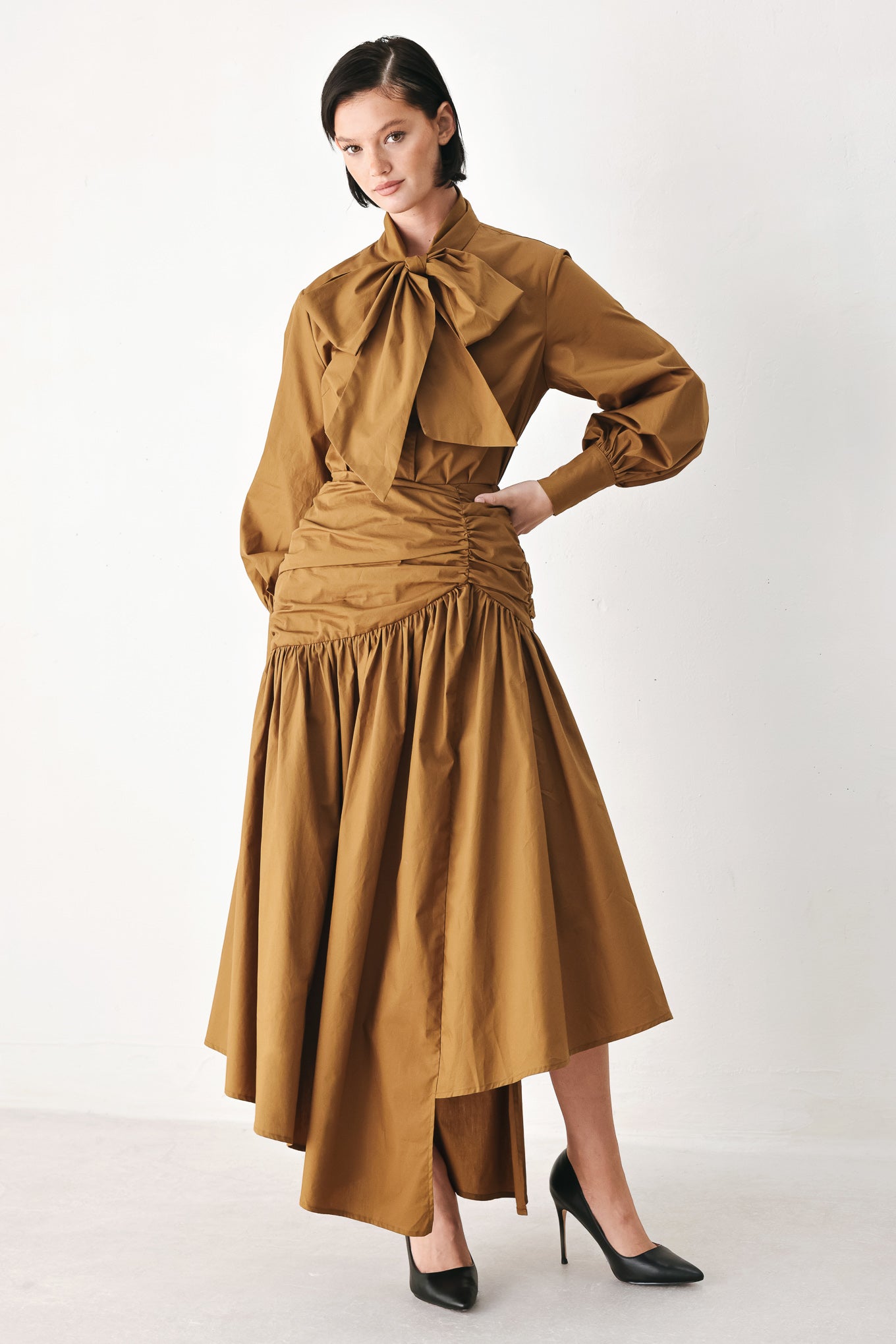 A model wearing a high-waisted, ruched A-line midi skirt in a warm caramel brown color | FREEMARKET