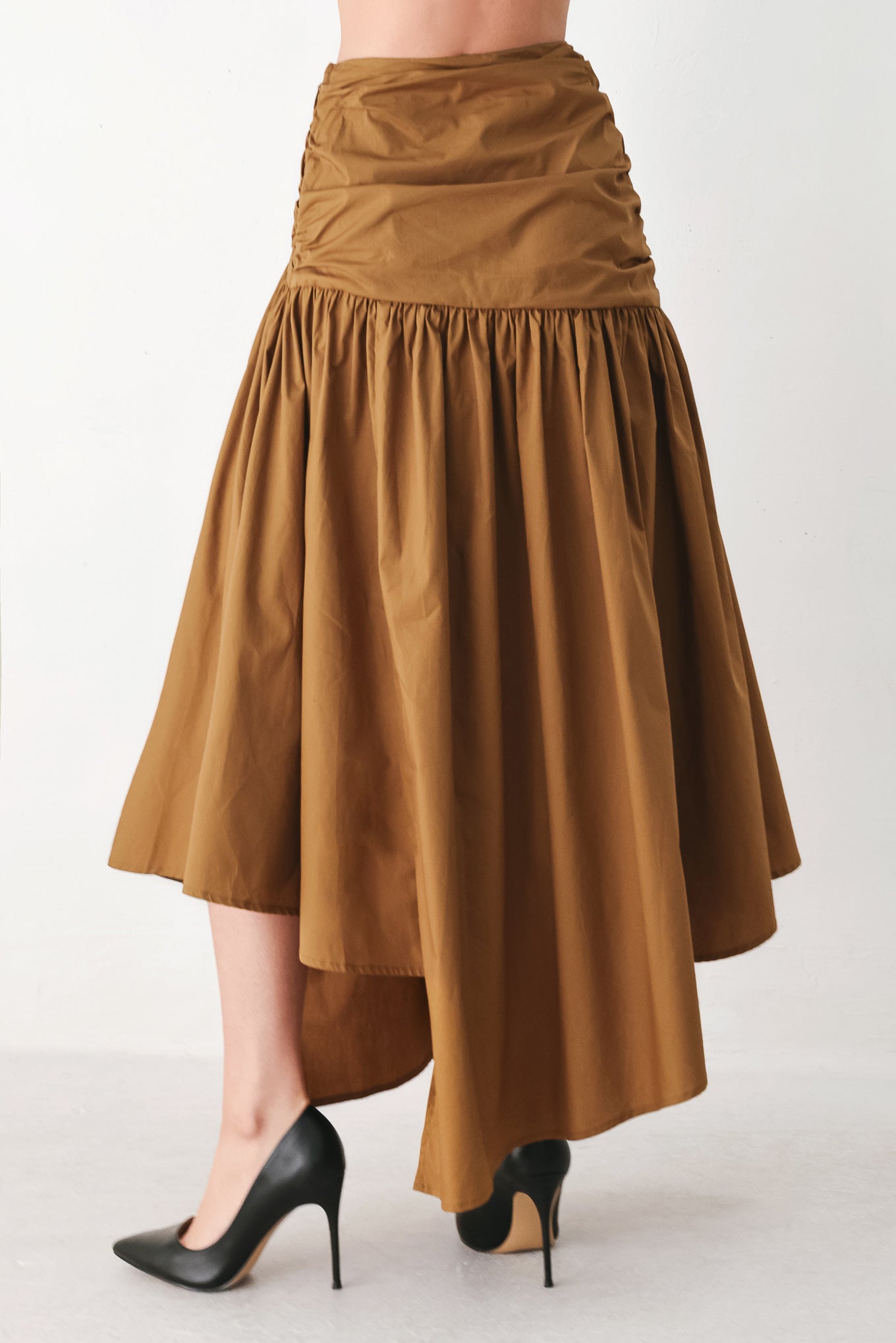 A model wearing a high-waisted, ruched A-line midi skirt in a warm caramel brown color | FREEMARKET