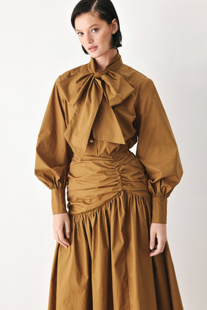 A model wearing a high-waisted, ruched A-line midi skirt in a warm caramel brown color | FREEMARKET