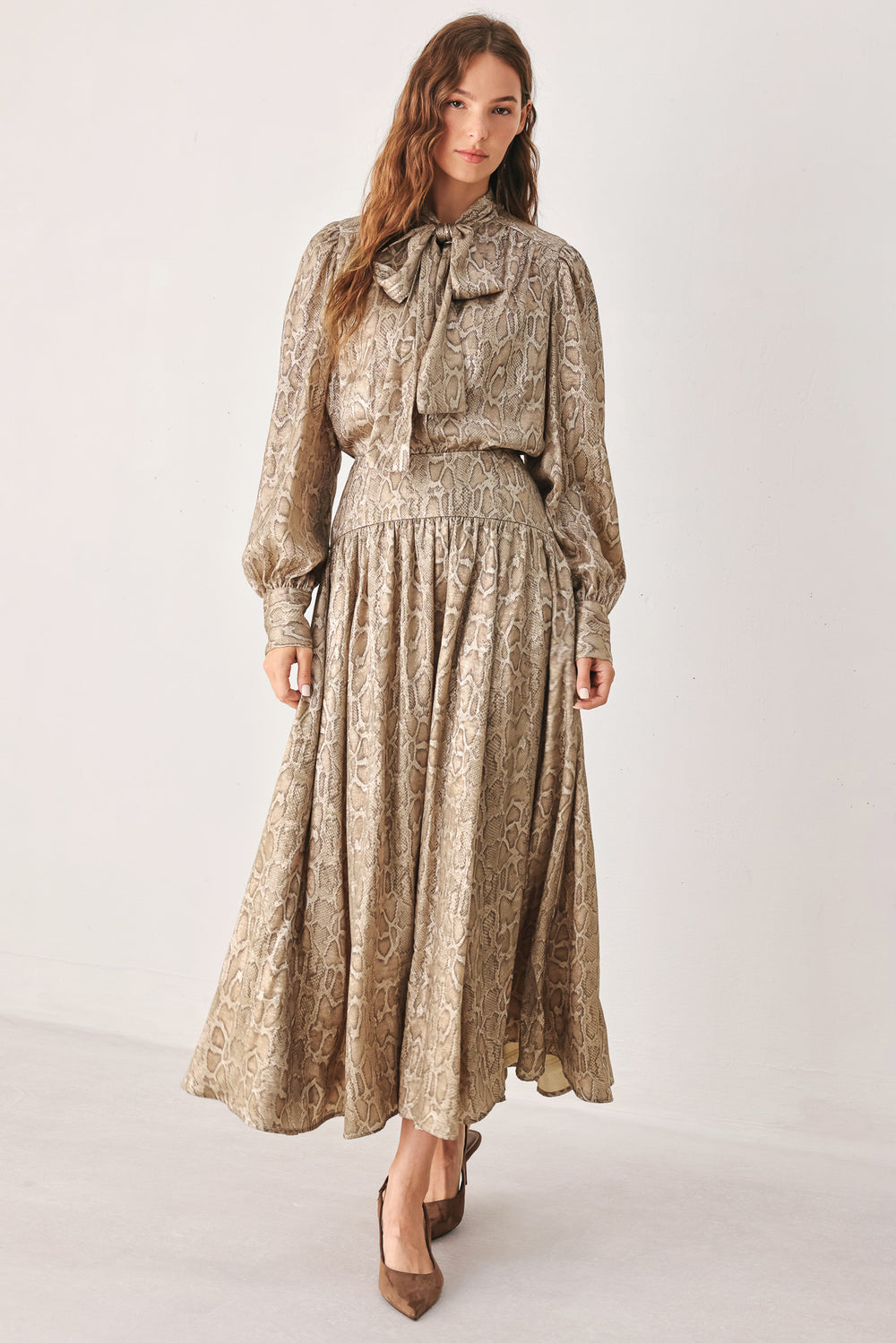 A woman wearing a high-waisted, A-line midi skirt with an all-over beige and brown snakeskin pattern | FREEMARKET