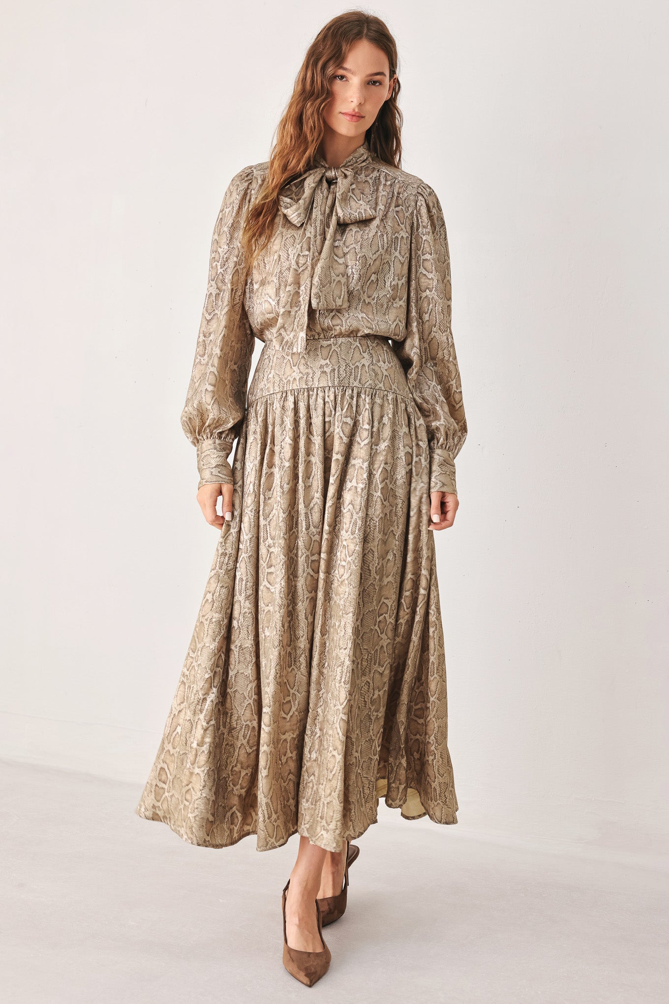 A woman wearing a high-waisted, A-line midi skirt with an all-over beige and brown snakeskin pattern | FREEMARKET