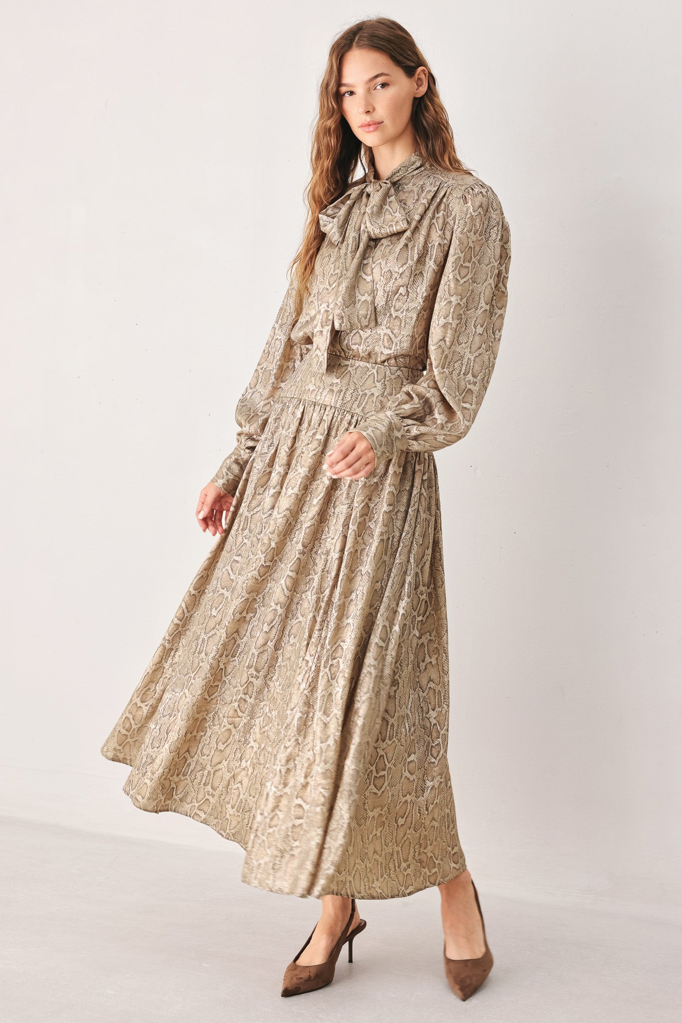 A woman wearing a high-waisted, A-line midi skirt with an all-over beige and brown snakeskin pattern | FREEMARKET