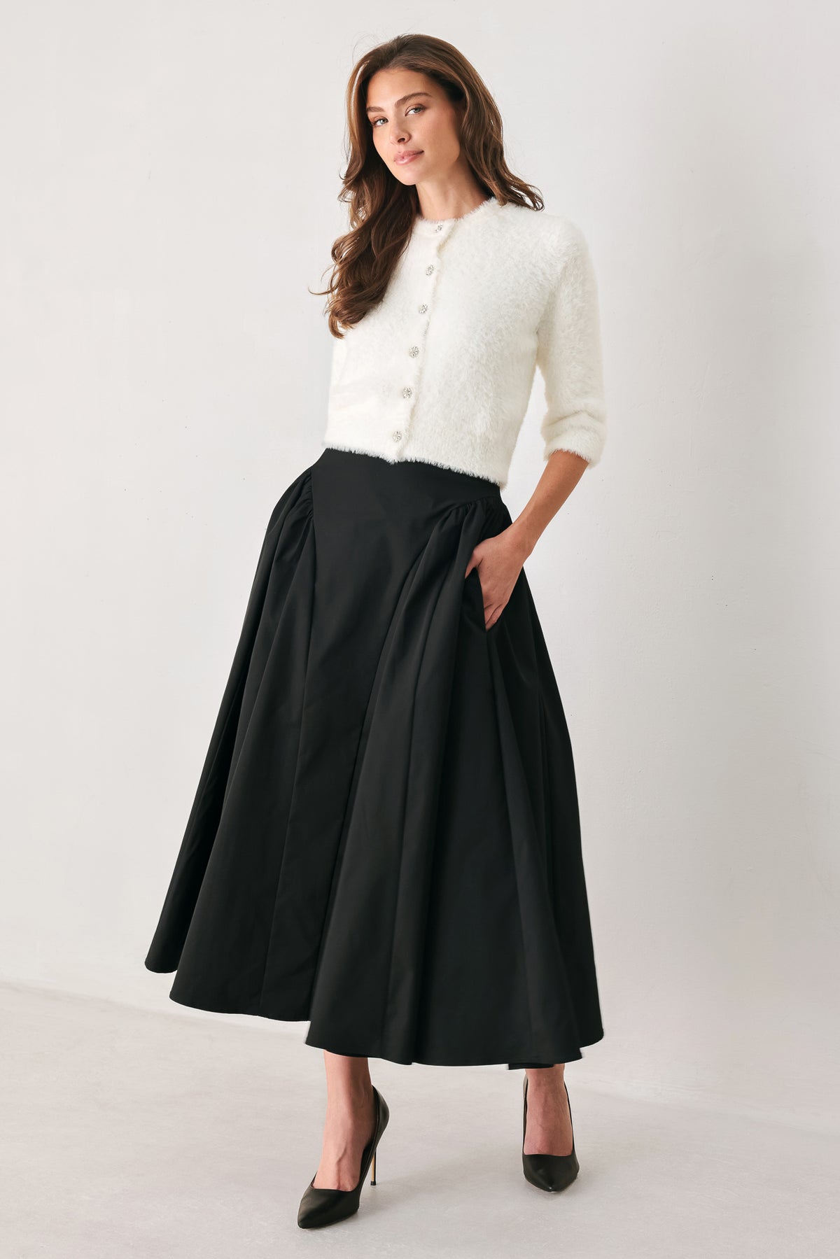 Woman wearing a high waisted black midi skirt with side shirring along the hips | FREEMARKET