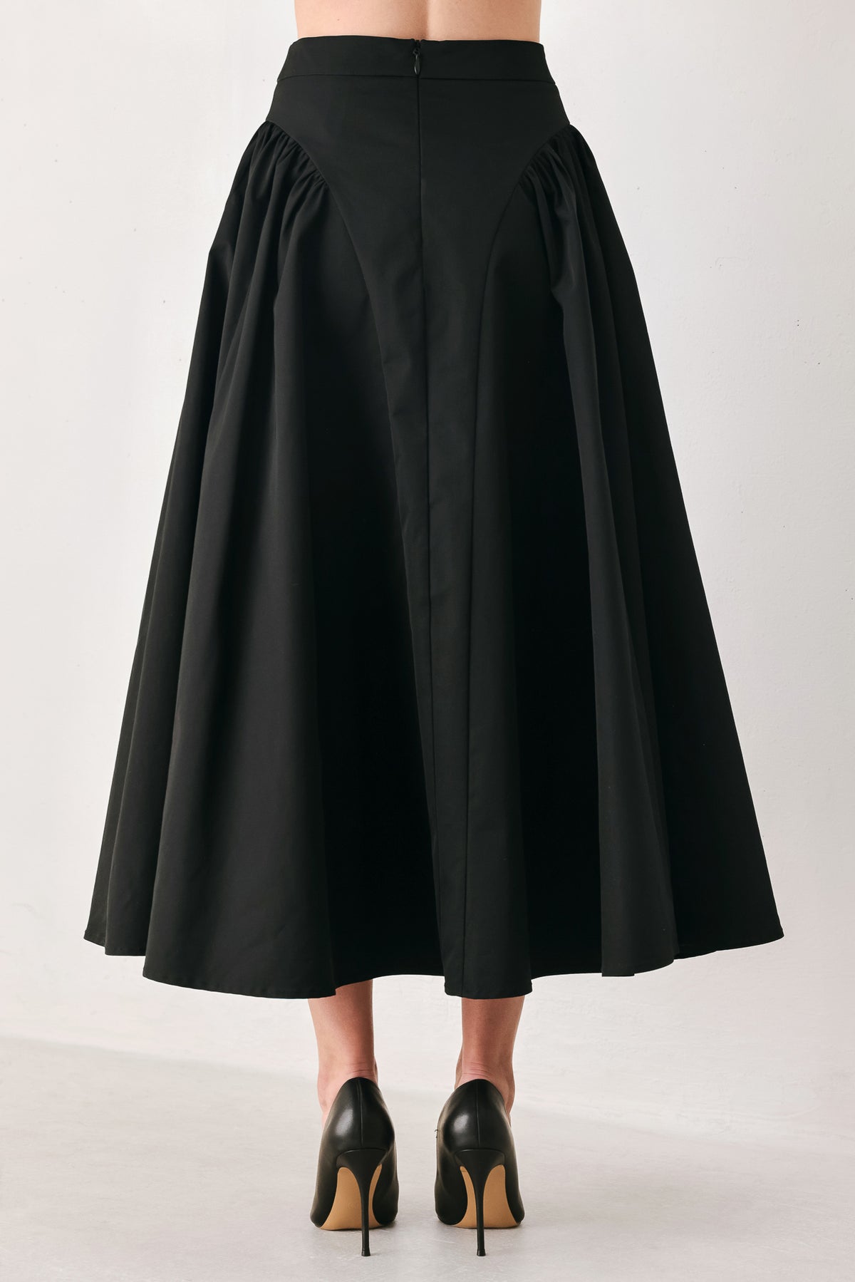 Woman wearing a high waisted black midi skirt with side shirring along the hips | FREEMARKET