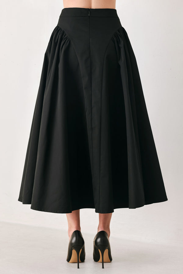 Woman wearing a high waisted black midi skirt with side shirring along the hips | FREEMARKET