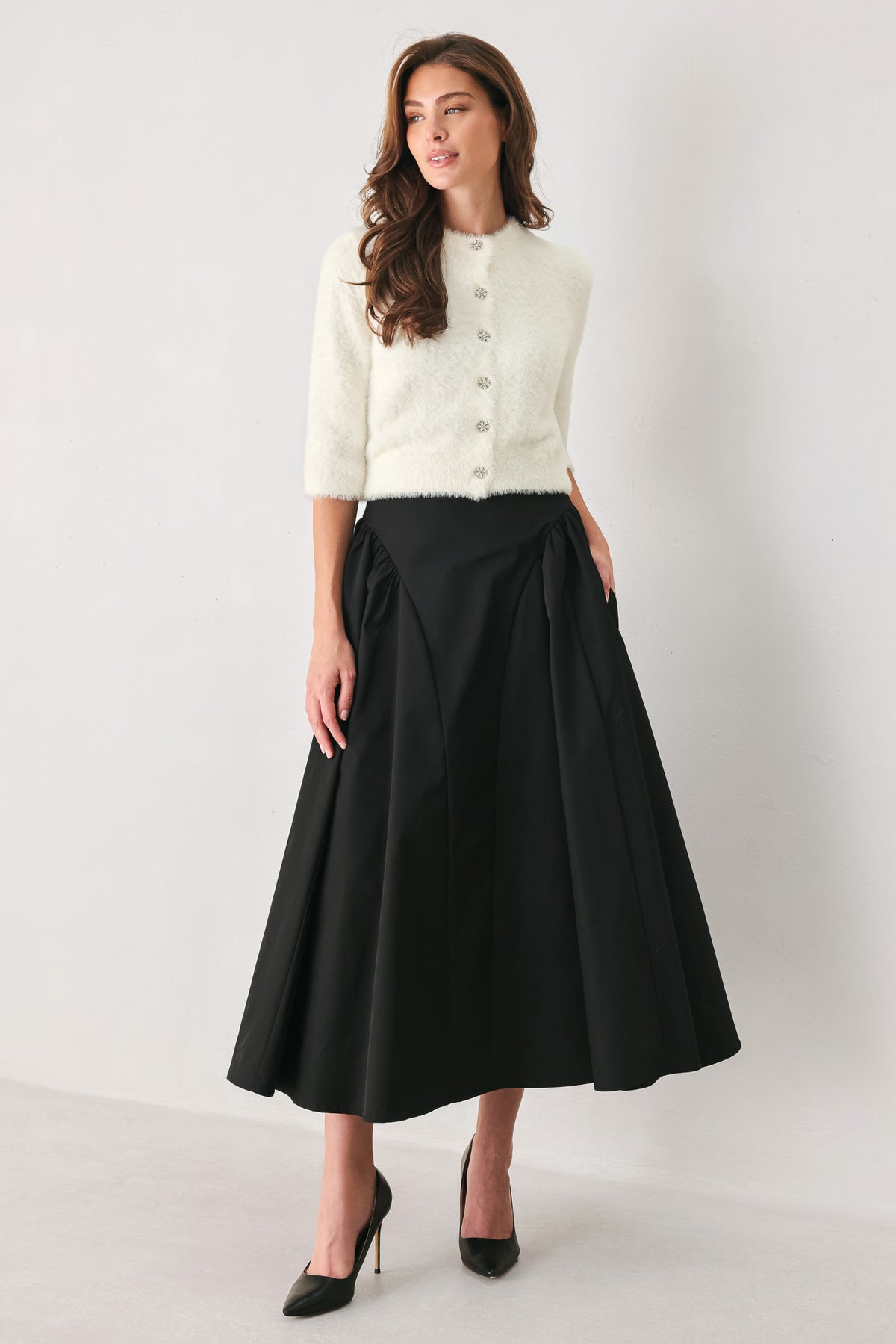 Woman wearing a high waisted black midi skirt with side shirring along the hips | FREEMARKET