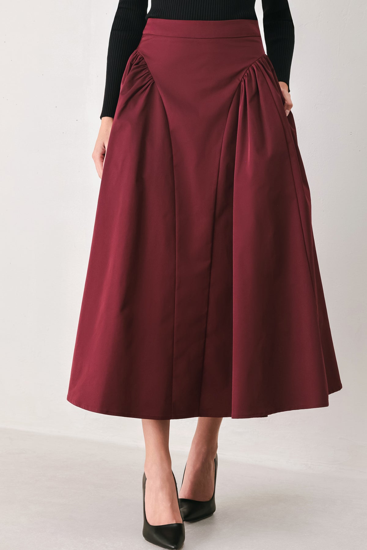 Woman wearing a high waisted burgundy midi skirt with side shirring along the hips | FREEMARKET