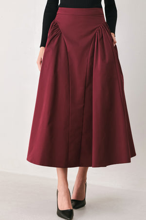 Woman wearing a high waisted burgundy midi skirt with side shirring along the hips | FREEMARKET