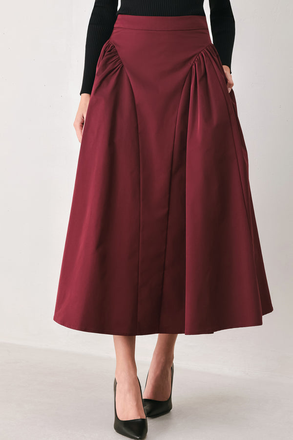 Woman wearing a high waisted burgundy midi skirt with side shirring along the hips | FREEMARKET
