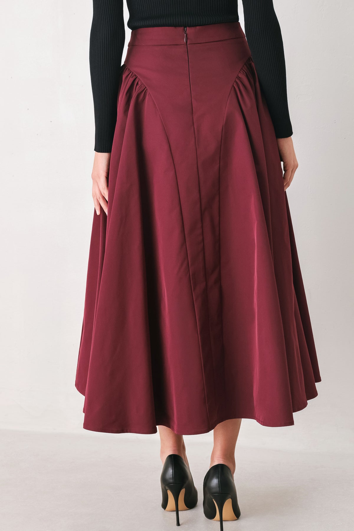Woman wearing a high waisted burgundy midi skirt with side shirring along the hips | FREEMARKET