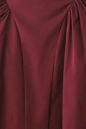 Woman wearing a high waisted burgundy midi skirt with side shirring along the hips | FREEMARKET
