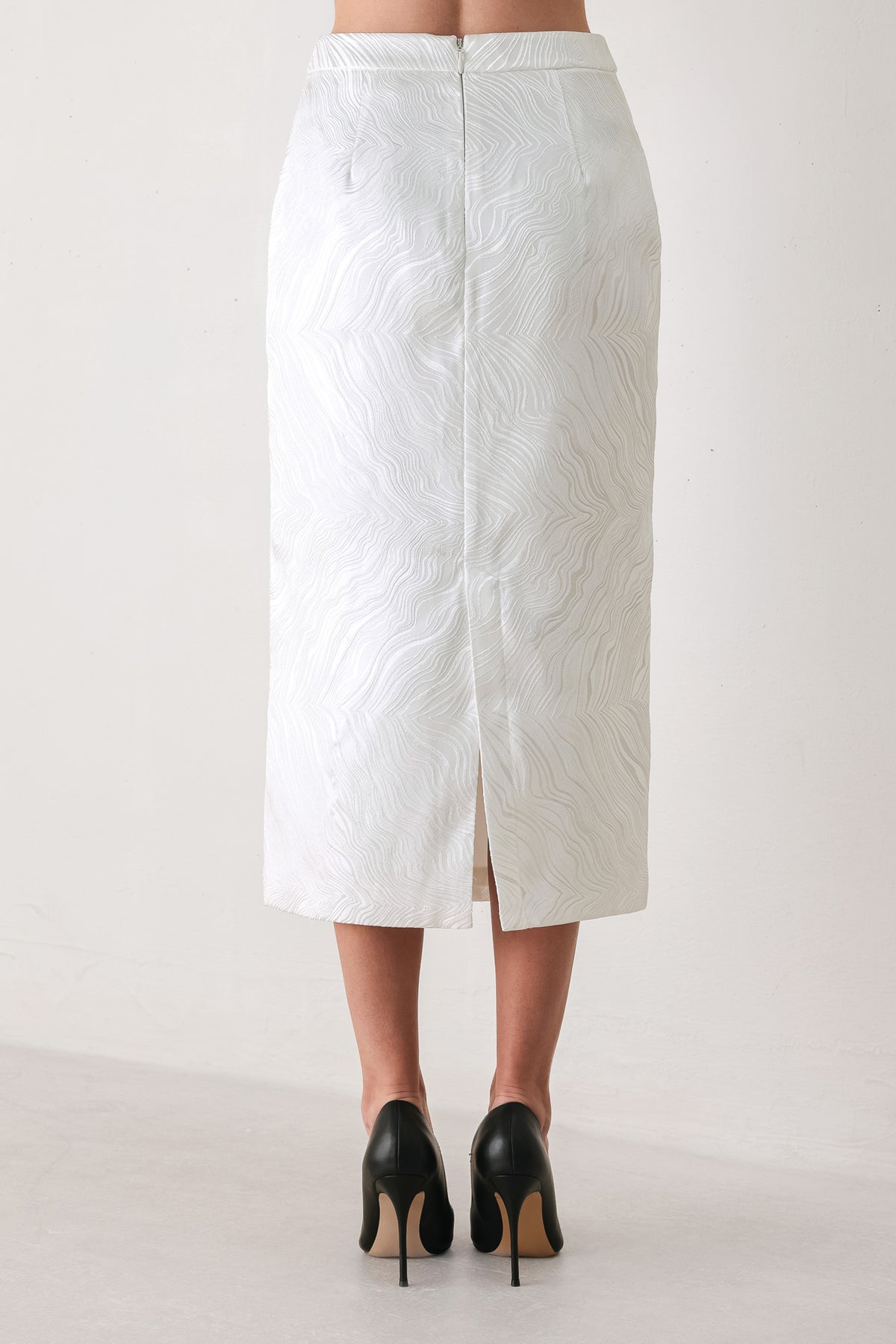 A white midi skirt with a subtle textured, wavy jacquard pattern, shown on a model | FREEMARKET