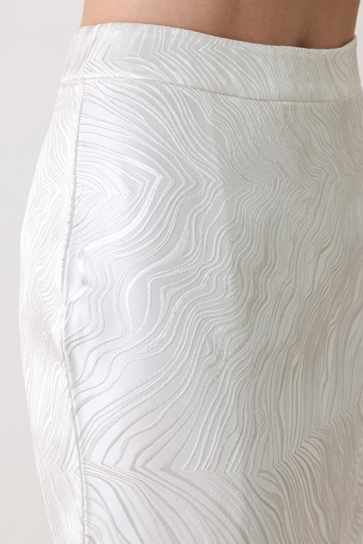 A white midi skirt with a subtle textured, wavy jacquard pattern, shown on a model | FREEMARKET