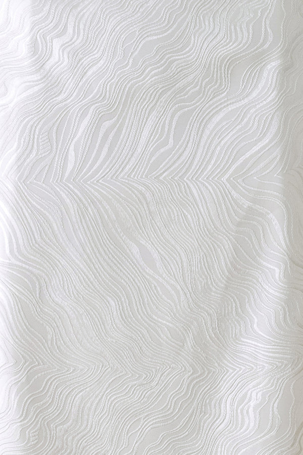 A white midi skirt with a subtle textured, wavy jacquard pattern, shown on a model | FREEMARKET