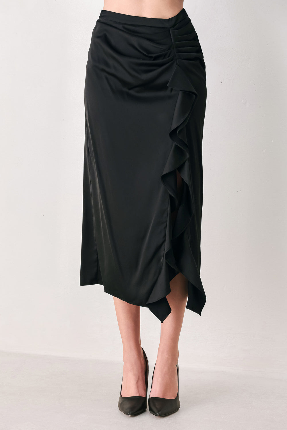 A black midi skirt with a draped, gathered waist and cascading ruffle detail along the side, shown on a model | FREEMARKET