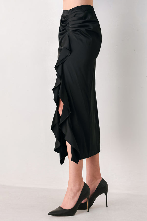 A black midi skirt with a draped, gathered waist and cascading ruffle detail along the side, shown on a model | FREEMARKET