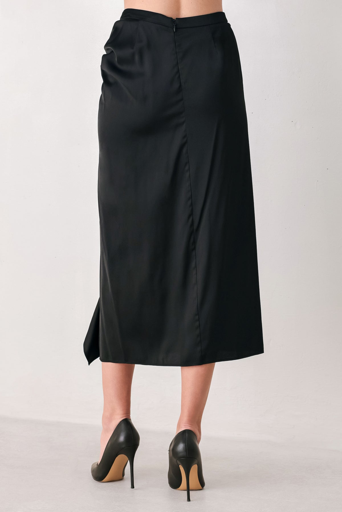 A black midi skirt with a draped, gathered waist and cascading ruffle detail along the side, shown on a model | FREEMARKET