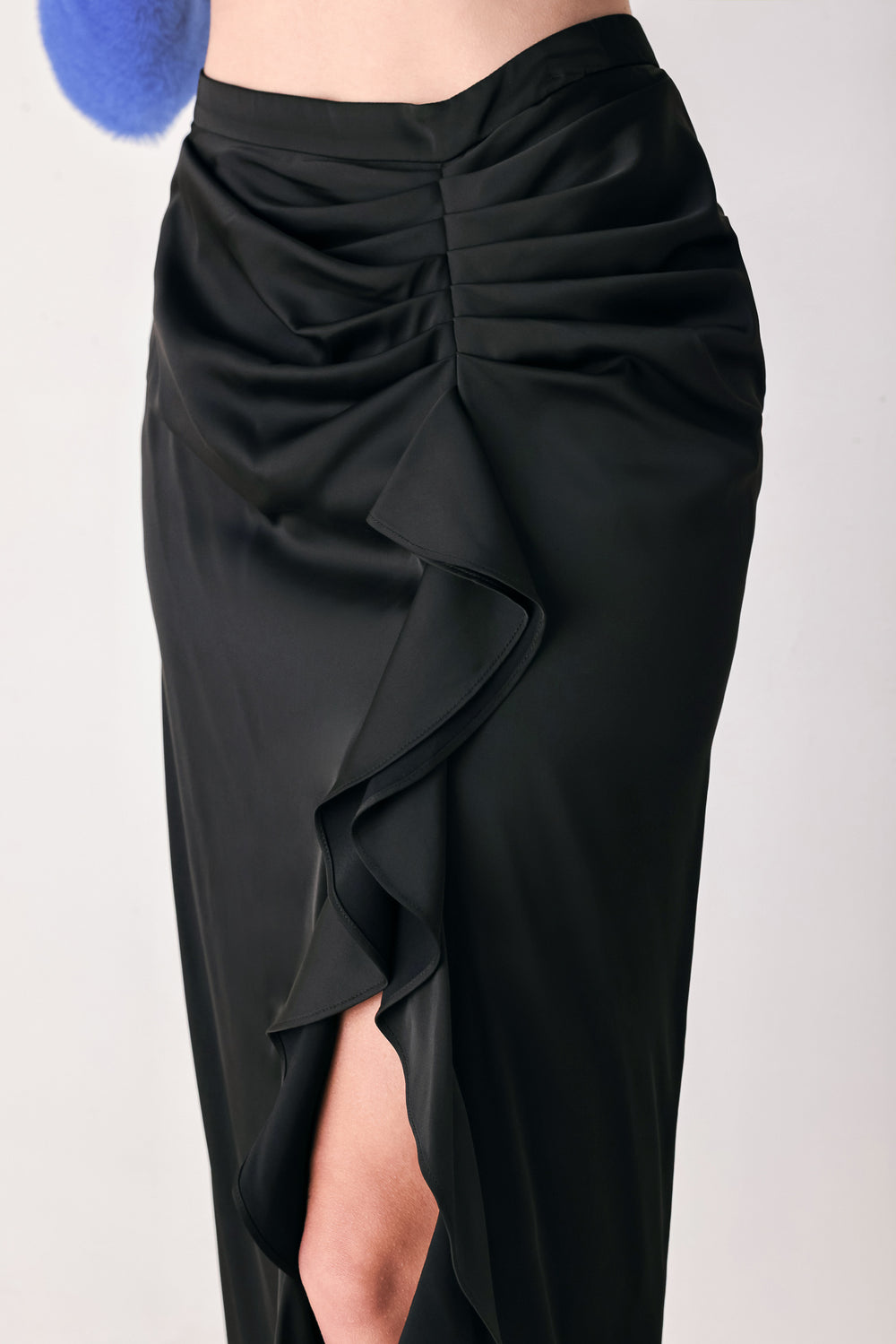 A black midi skirt with a draped, gathered waist and cascading ruffle detail along the side, shown on a model | FREEMARKET