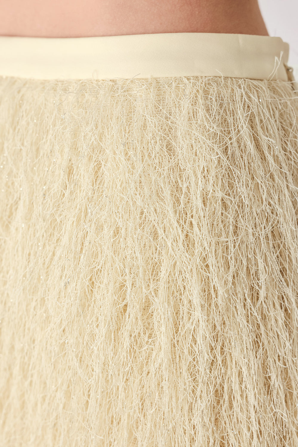 A close-up of a model wearing a cream-colored, shaggy, textured mini skirt | FREEMARKET
