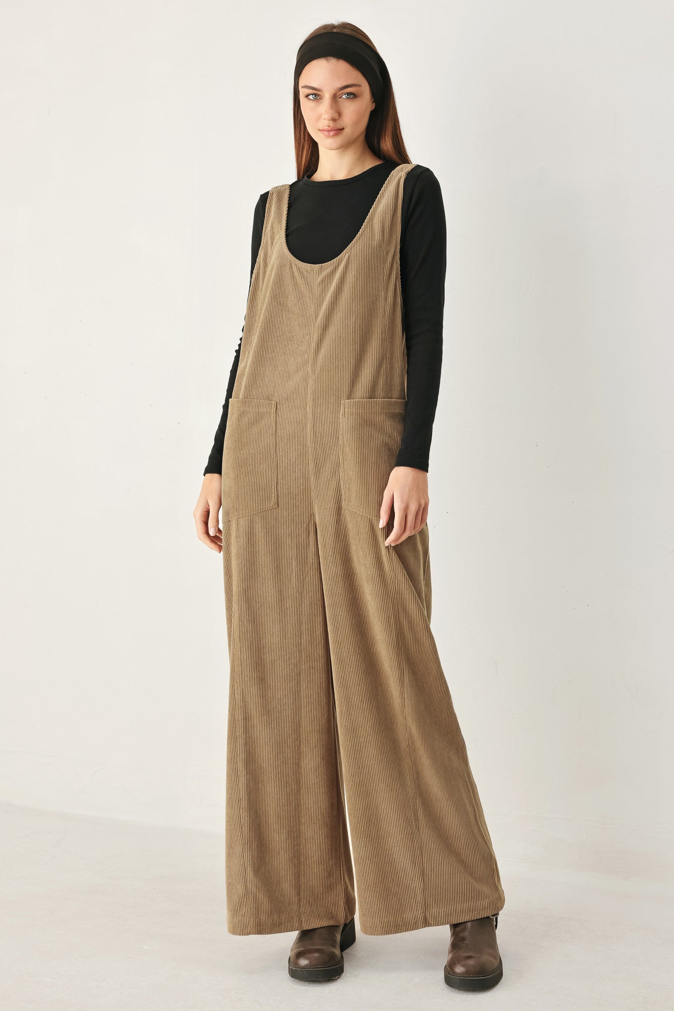 Woman wearing a brown corduroy jumpsuit with U neckline, pockets and adjustable straps | FREEMARKET