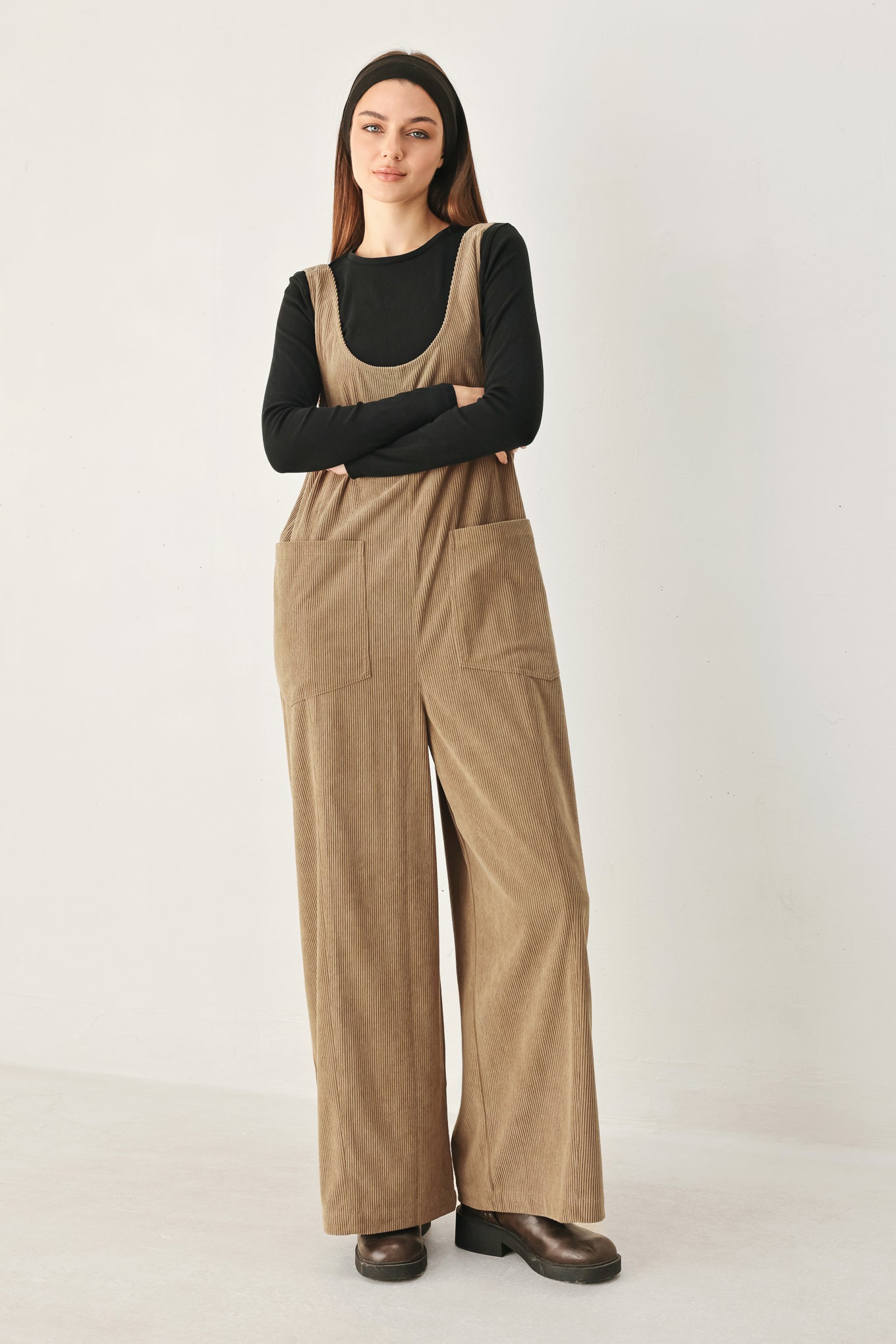 Woman wearing a brown corduroy jumpsuit with U neckline, pockets and adjustable straps | FREEMARKET