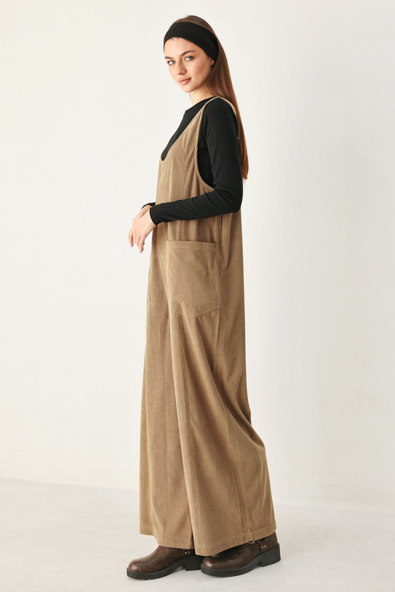 Woman wearing a brown corduroy jumpsuit with U neckline, pockets and adjustable straps | FREEMARKET