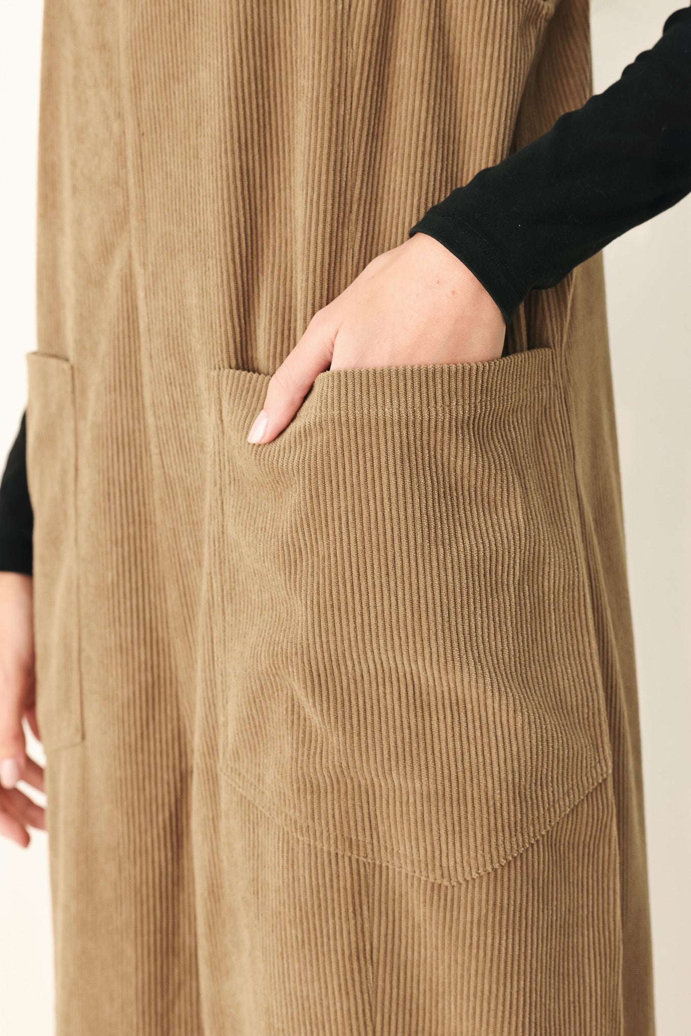 Woman wearing a brown corduroy jumpsuit with U neckline, pockets and adjustable straps | FREEMARKET