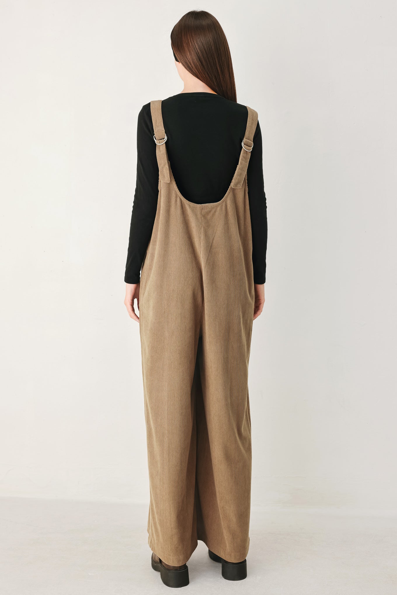 Woman wearing a brown corduroy jumpsuit with U neckline, pockets and adjustable straps | FREEMARKET