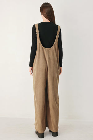 Woman wearing a brown corduroy jumpsuit with U neckline, pockets and adjustable straps | FREEMARKET