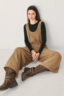 Woman wearing a brown corduroy jumpsuit with U neckline, pockets and adjustable straps | FREEMARKET