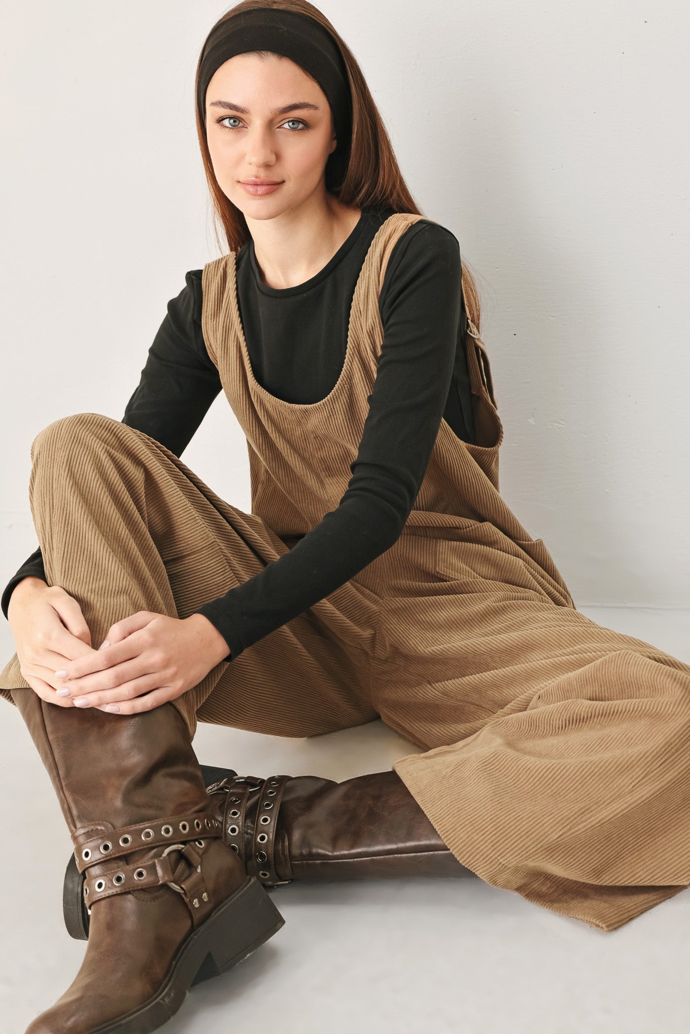 Woman wearing a brown corduroy jumpsuit with U neckline, pockets and adjustable straps | FREEMARKET