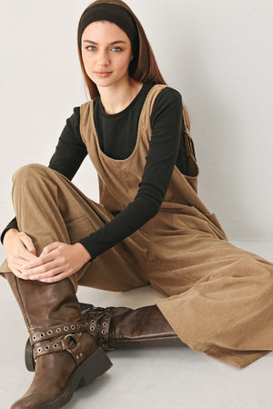 Woman wearing a brown corduroy jumpsuit with U neckline, pockets and adjustable straps | FREEMARKET