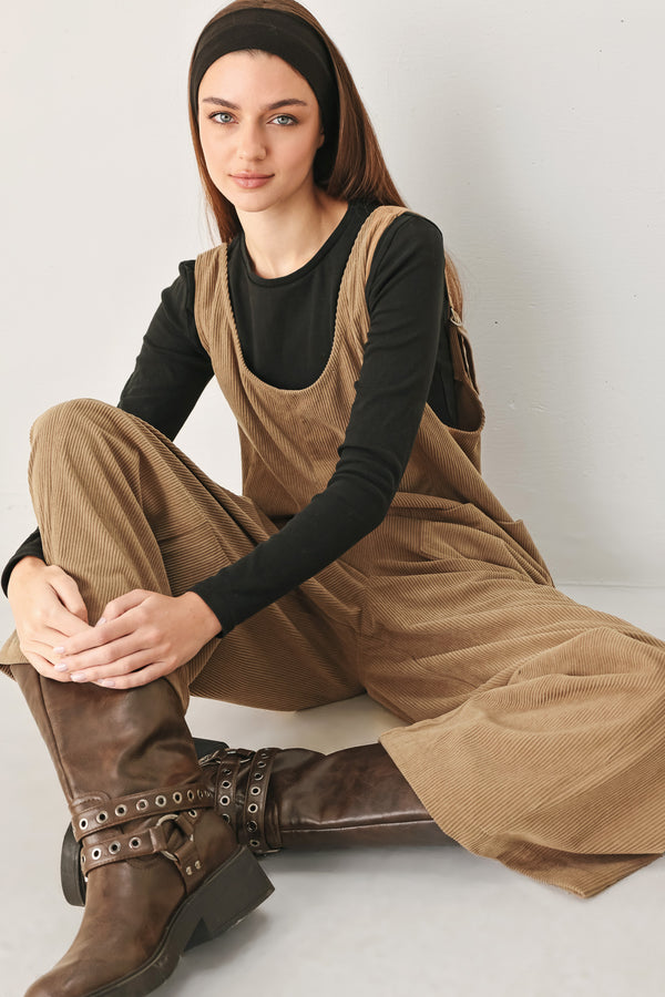 Woman wearing a brown corduroy jumpsuit with U neckline, pockets and adjustable straps | FREEMARKET
