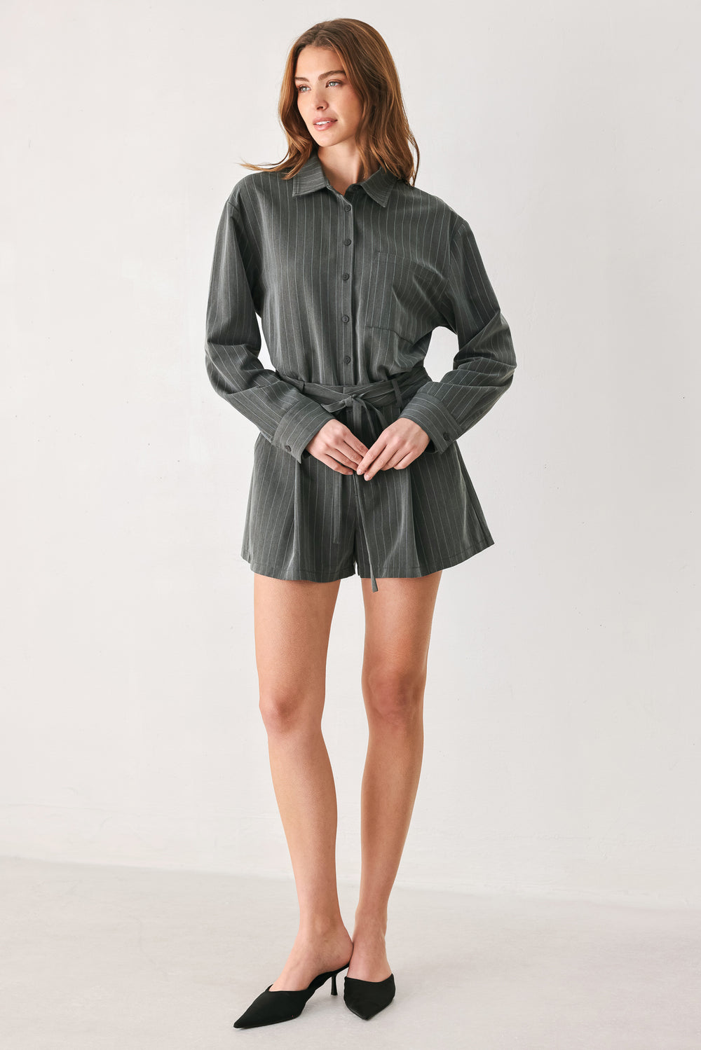 A woman modeling a dark gray pinstriped long-sleeve shirt dress with a tie waist belt | FREEMARKET 