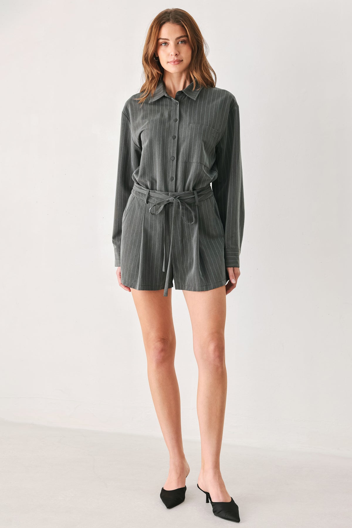 A woman modeling a dark gray pinstriped long-sleeve shirt dress with a tie waist belt | FREEMARKET 