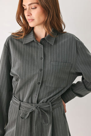 A woman modeling a dark gray pinstriped long-sleeve shirt dress with a tie waist belt | FREEMARKET 