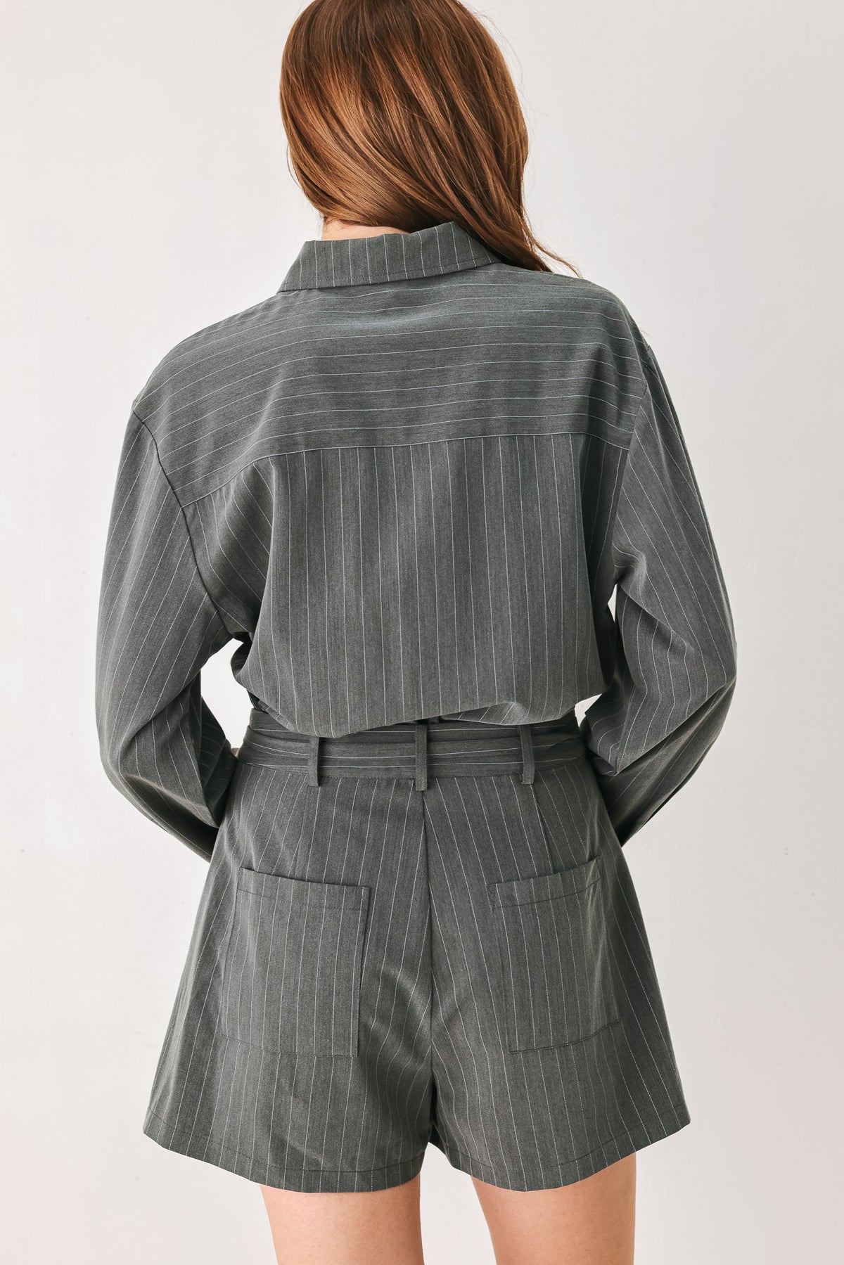 A woman modeling a dark gray pinstriped long-sleeve shirt dress with a tie waist belt | FREEMARKET 