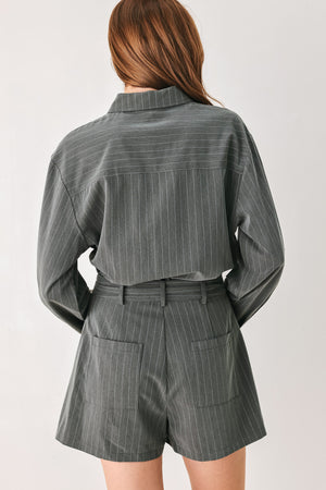 A woman modeling a dark gray pinstriped long-sleeve shirt dress with a tie waist belt | FREEMARKET 