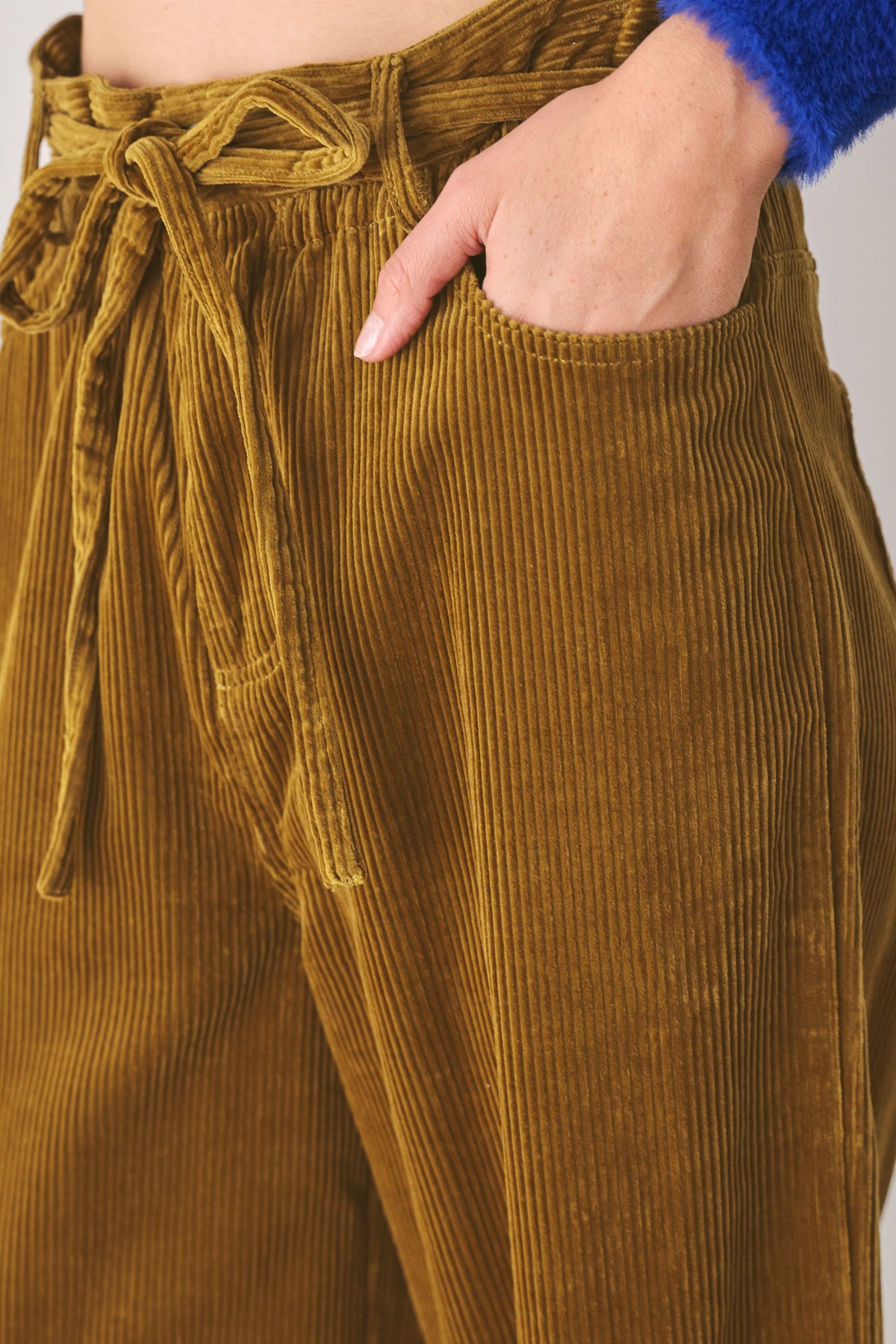 A woman modeling a high-waisted, wide-leg brown corduroy pants with a drawstring waist | FREEMARKET
