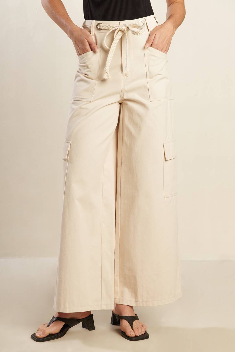 A solid woven pant featuring front closure, contrasting belt, side and cargo pockets and wide leg.