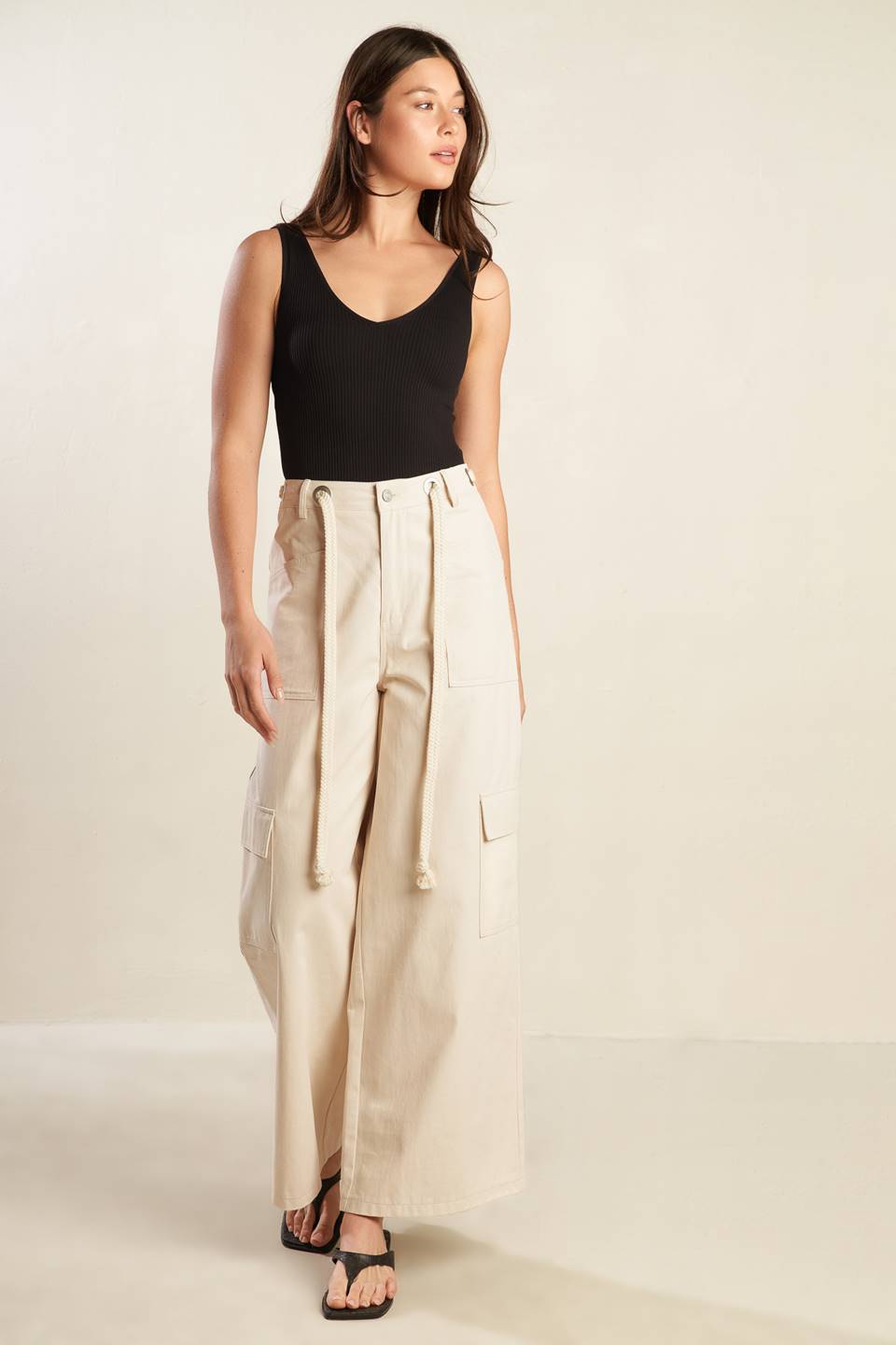 A solid woven pant featuring front closure, contrasting belt, side and cargo pockets and wide leg.