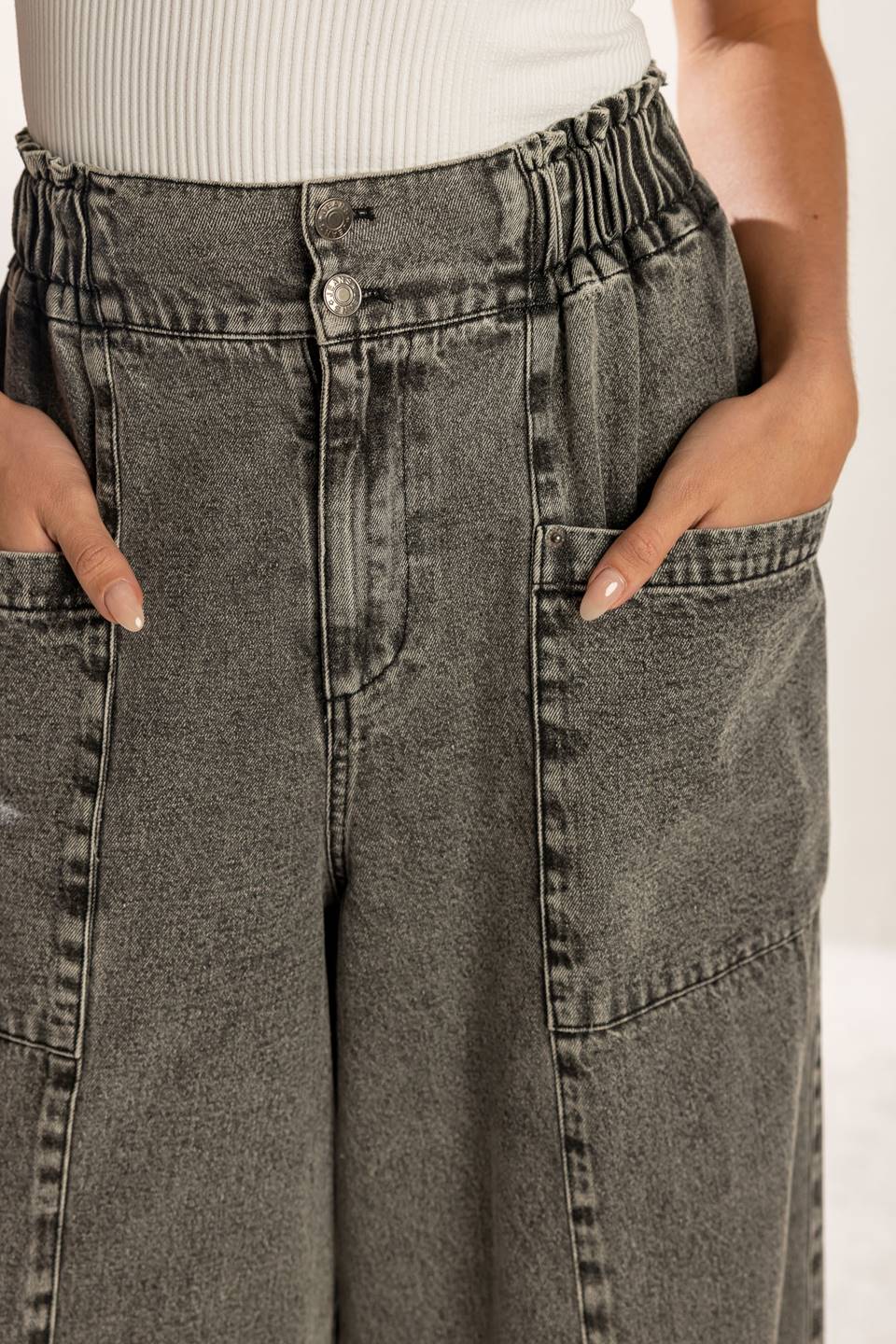 A washed denim pant featuring elasticized waistband, front zipper closure, side pockets and wide leg.