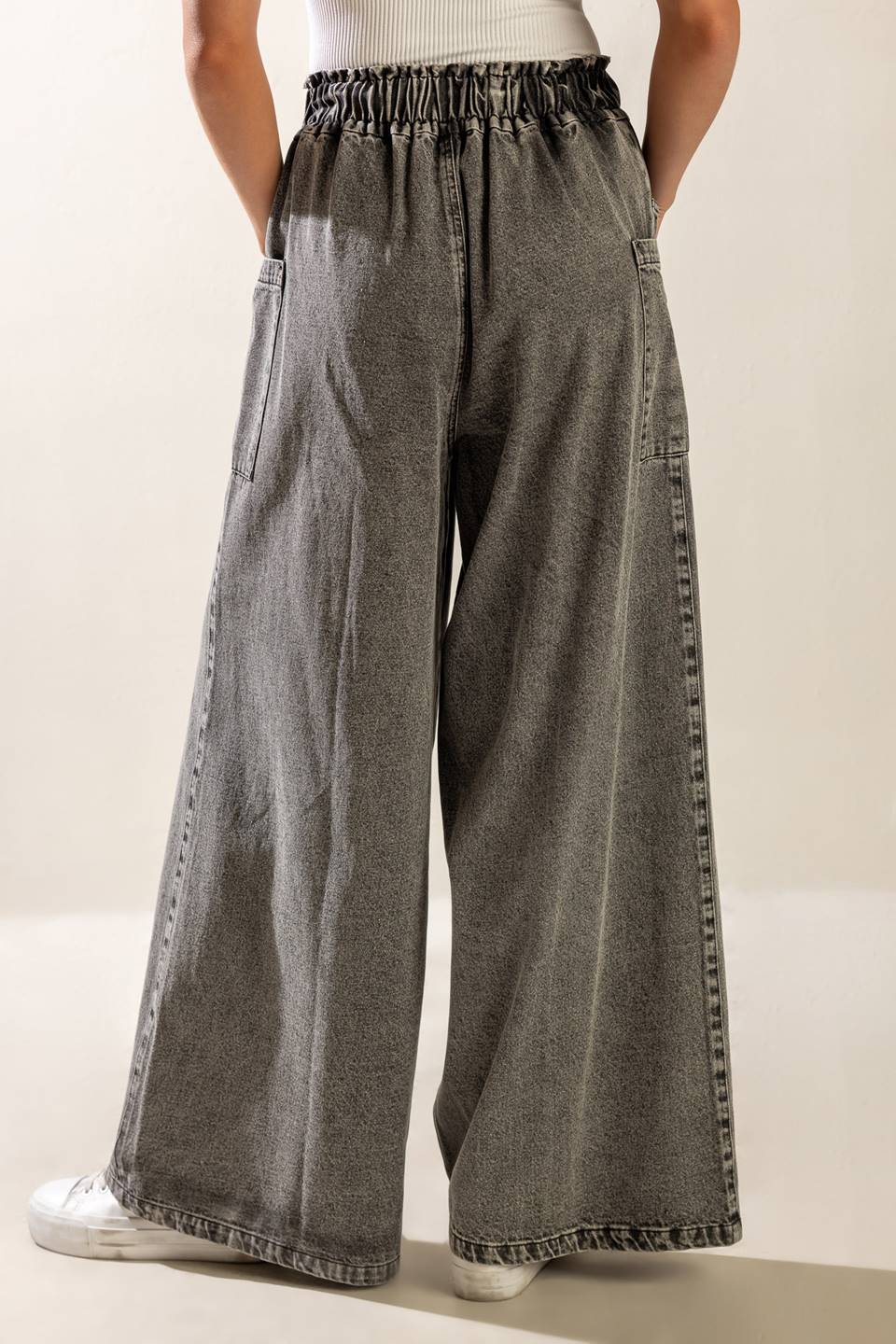 A washed denim pant featuring elasticized waistband, front zipper closure, side pockets and wide leg.