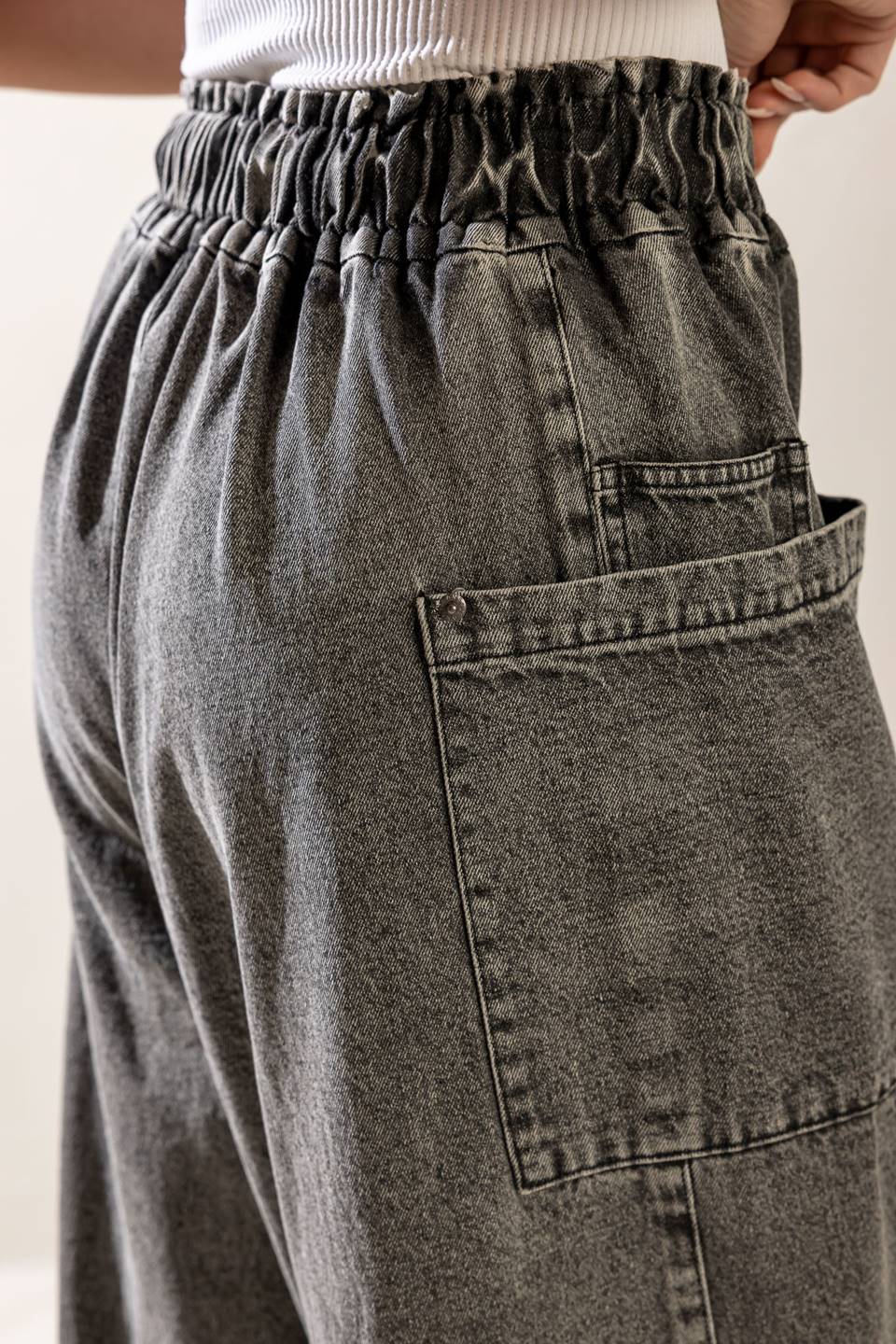 A washed denim pant featuring elasticized waistband, front zipper closure, side pockets and wide leg.