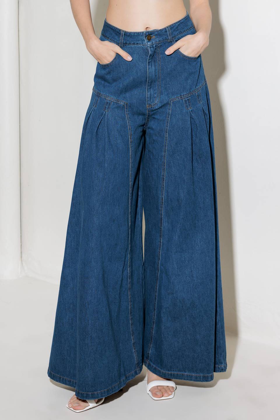 A washed denim pant featuring front closure, side pockets, side pleating detail and extra wide leg.