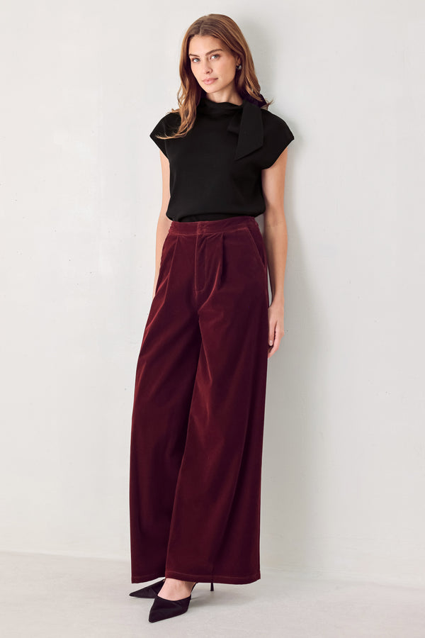 A person wearing high-waisted, wide-leg burgundy velvet pants with black pointed-toe heels | FREEMARKET