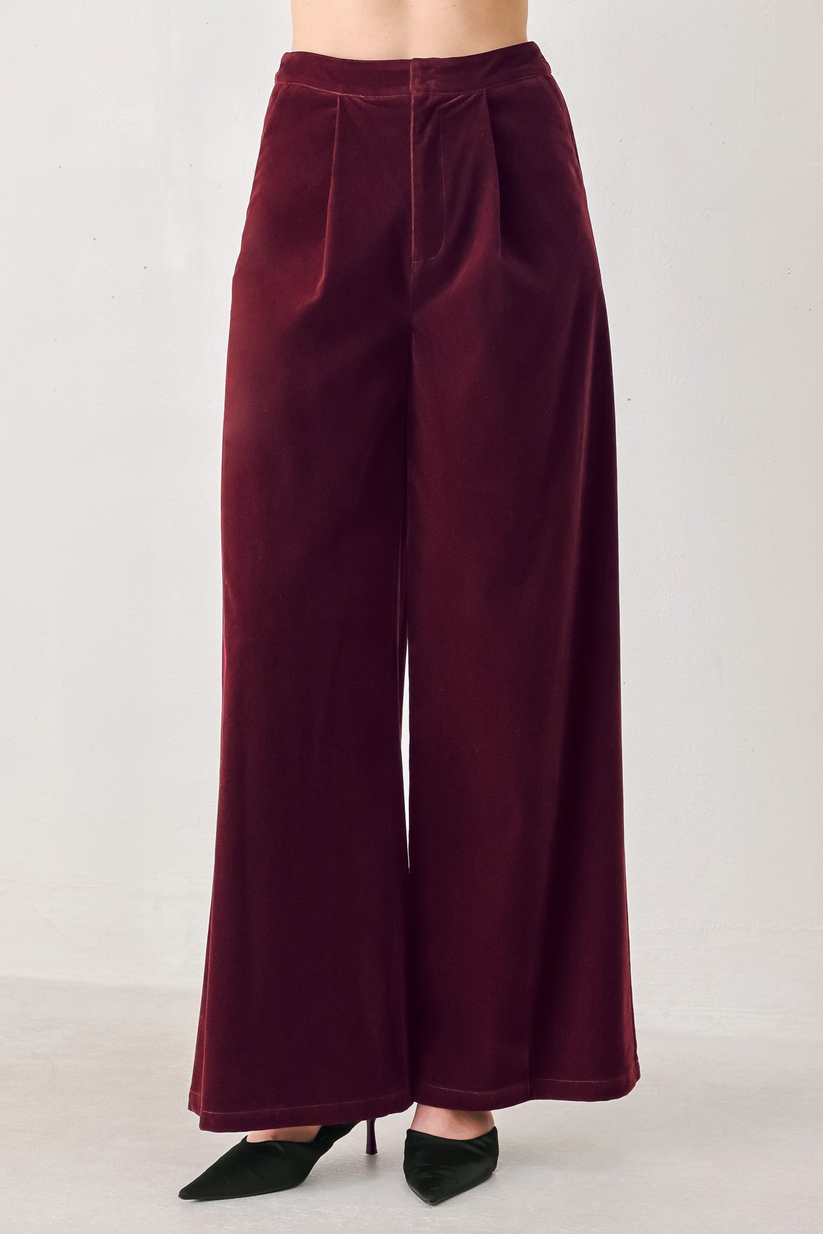 A person wearing high-waisted, wide-leg burgundy velvet pants with black pointed-toe heels | FREEMARKET